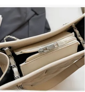 Détail macro du zip argenté et de la texture matelassée du sac beige crème