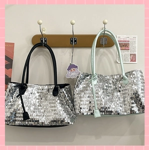 Detail of silver sequin tote bags with black and mint green leather handles