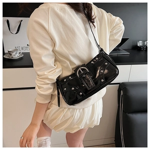 Détail du sac sous le bras en cuir verni noir avec rivets argentés et large boucle