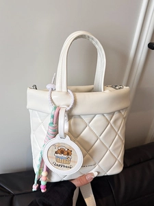 Borsa a secchiello bianca trapuntata con ricamo e ciondolo capibara tenuta in mano