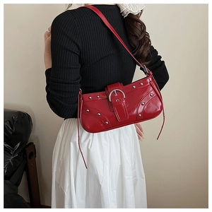 Détail du sac sous le bras en cuir verni rouge avec rivets argentés et grande boucle