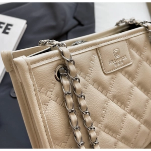 Vue détaillée du sac matelassé beige avec chaîne dorée et broderie du logo
