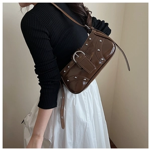Détail d'un sac baguette Y2K en cuir verni marron avec rivets et boucle argentés