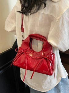 Fashionable red dumpling bag in glossy patent leather with bow ties and shoulder strap