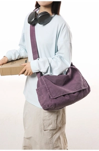Detailed view of a purple canvas messenger bag with a wide strap on a model