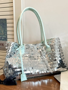Chic silver sequin tote bag with mint green faux leather trim in an urban setting
