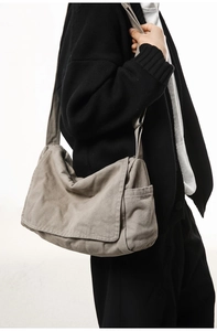 Detail view of a large grey canvas messenger bag with a flap cover and side pocket