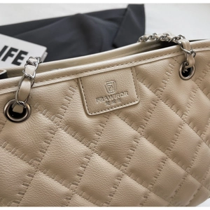 Gros plan sur le sac à bandoulière en cuir beige matelassé avec chaîne en argent