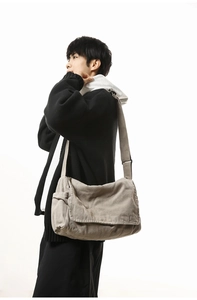 Side view of taupe canvas messenger bag with wide shoulder strap on a male model