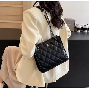 Détail d'un sac bandoulière noir matelassé avec chaîne et logo de marque argenté