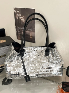 Chic silver sequin tote bag with black leather handles and reflective metallic finish