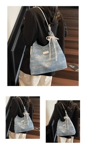 Detail of light blue tote bag featuring delicate lace bows and pearl chain embellishments