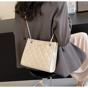 Détail d'un sac à bandoulière matelassé crème porté avec un blazer gris professionnel