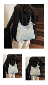 Close-up of light blue denim hobo bag featuring lace bow and pearl pendant details