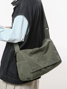 Large military green canvas messenger bag with adjustable strap worn by a model