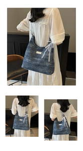 Detail of blue denim tote bag featuring lace bow, pearl charm and white woven label