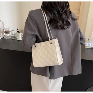 Mannequin portant un sac matelassé beige avec chaîne argentée dans un décor de café