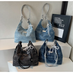 Detail of four denim hobo bags with lace bows and pearl charms on a tiered stand