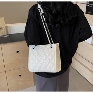 Détail d'un sac cabas blanc matelassé avec bandoulière chaîne et texture cuir luxe