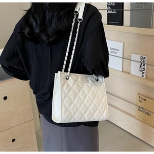 Détail du sac bandoulière blanc matelassé avec logo de marque argenté et bandoulière chaîne