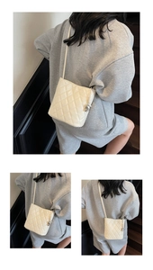 Détail du sac bandoulière beige matelassé avec charm cœur et finition lisse brillante