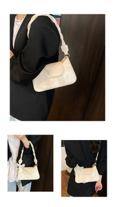 Detail of cream underarm bag with woven strap, marble texture, and lace bow accessory