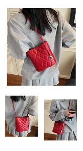 Détails d'un sac seau rouge matelassé avec pendentif métallique et coutures en losange