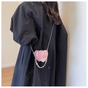 Detail of pink heart-shaped mini crossbody bag with embossed text and pearl chain