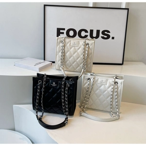 Détail de sacs bandoulière matelassés en noir, blanc et beige avec chaîne en métal