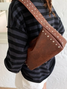Brown vintage PU leather shoulder bag with silver studs and wide strap on model back
