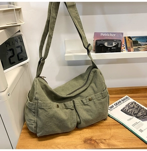 Detail der armeegrünen Canvas-Umhängetasche mit Retro-Taschen und verstellbarem Gurt