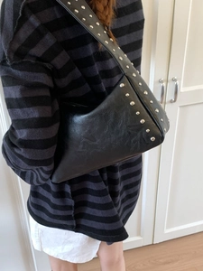 Fashionable black faux leather rivet shoulder bag with edgy asymmetrical punk style