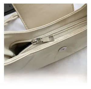 Detail view of cream-white faux leather shoulder bag with metal zipper and magnetic buckle