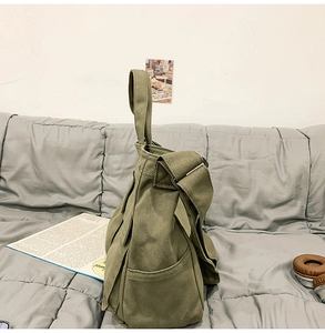Détail du cabas en toile vert armée avec poches latérales posé sur un canapé en tissu gris