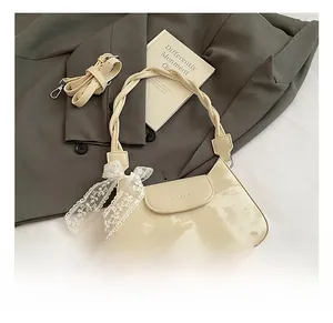 Close-up of cream crescent bag featuring braided handle and lace bow detail