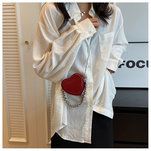 Close-up of heart-shaped mini crossbody bag in red PU leather with silver bead chain