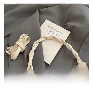 Macro view of woven chain handle and silver hardware on a beige underarm bag