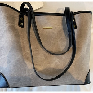 Close-up of dual-tone tote bag with stone-texture fabric and gold hardware details
