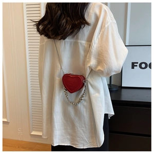 Detail of red heart-shaped leather mini bag with silver bead chain and embossed logo