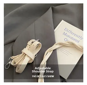 Detail of adjustable woven shoulder strap with silver metal buckle on a cream bag