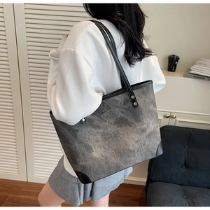 Detail of gray marble-textured large tote bag with black leather straps and gold rivets