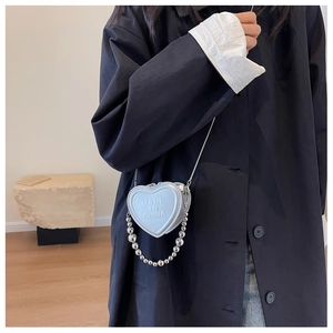 Detail of silver heart-shaped mini crossbody bag with embossed lettering and bead chain