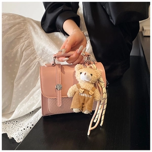 Pink leather handbag with woven texture and a cute brown plush bear charm detail