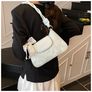 Detailed view of green marbled underarm bag with lace bow and rope strap on model