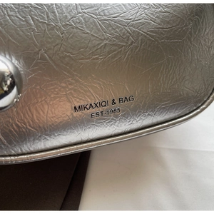Close-up of MIKAXIQI & BAG embossed logo on silver wrinkled leather texture