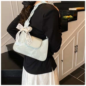 Detail view of light blue underarm bag featuring lace bow and twisted strap design