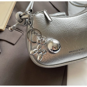 Detail of silver pleated shoulder bag with metallic dog charm and knotted rope strap