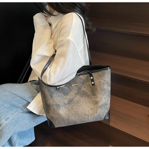 Detailed view of gray vintage tote bag with black leather trim and gold metal accent