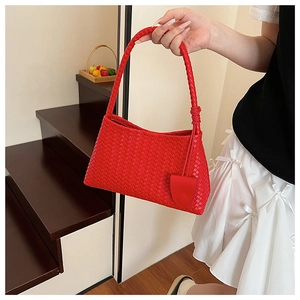 Detail of red hand-woven shoulder bag with intricate leather texture and matching tag