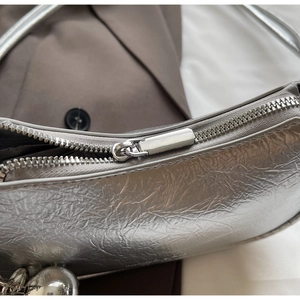 Macro view of silver pleated crescent bag showing metallic texture and zipper detail